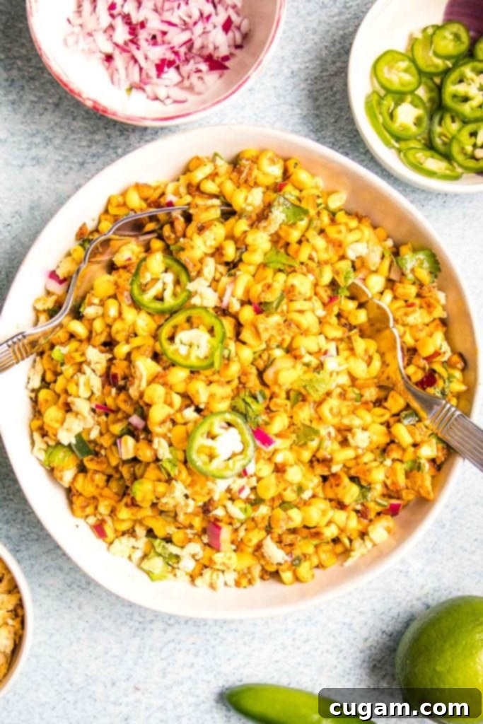 Delicious Vegan Mexican Street Corn 17 White bowl filled with Mexican street corn salad with small bowls of extra red onion, limes, jalapenos for garnish, ready to be served.