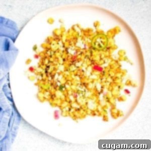 Delicious Vegan Mexican Street Corn 18 Mexican Street Corn Salad with red onions, jalapenos, cilantro and spices on a large white rimmed plate atop a blue napkin