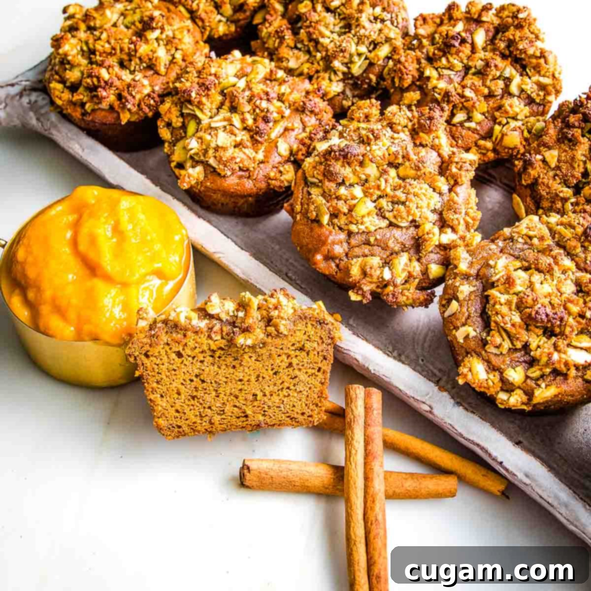 Tray of pumpkin muffins. One is cut open to see the texture.