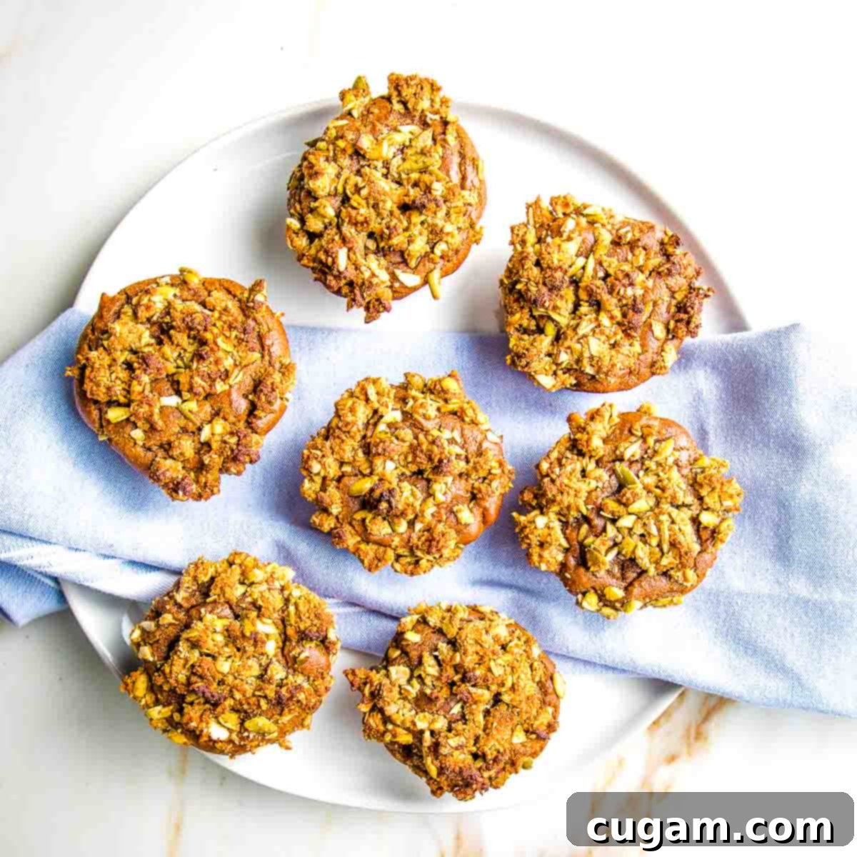 Pumpkin muffins with streusel topping on a round plate with blue cloth napkin.