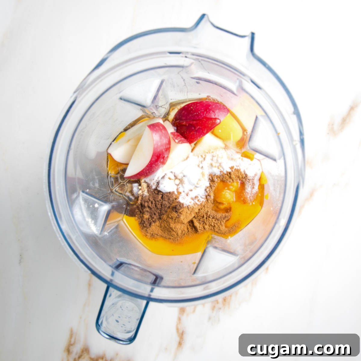 Ingredients in a blender: apple slices, almond flour, spices, eggs.