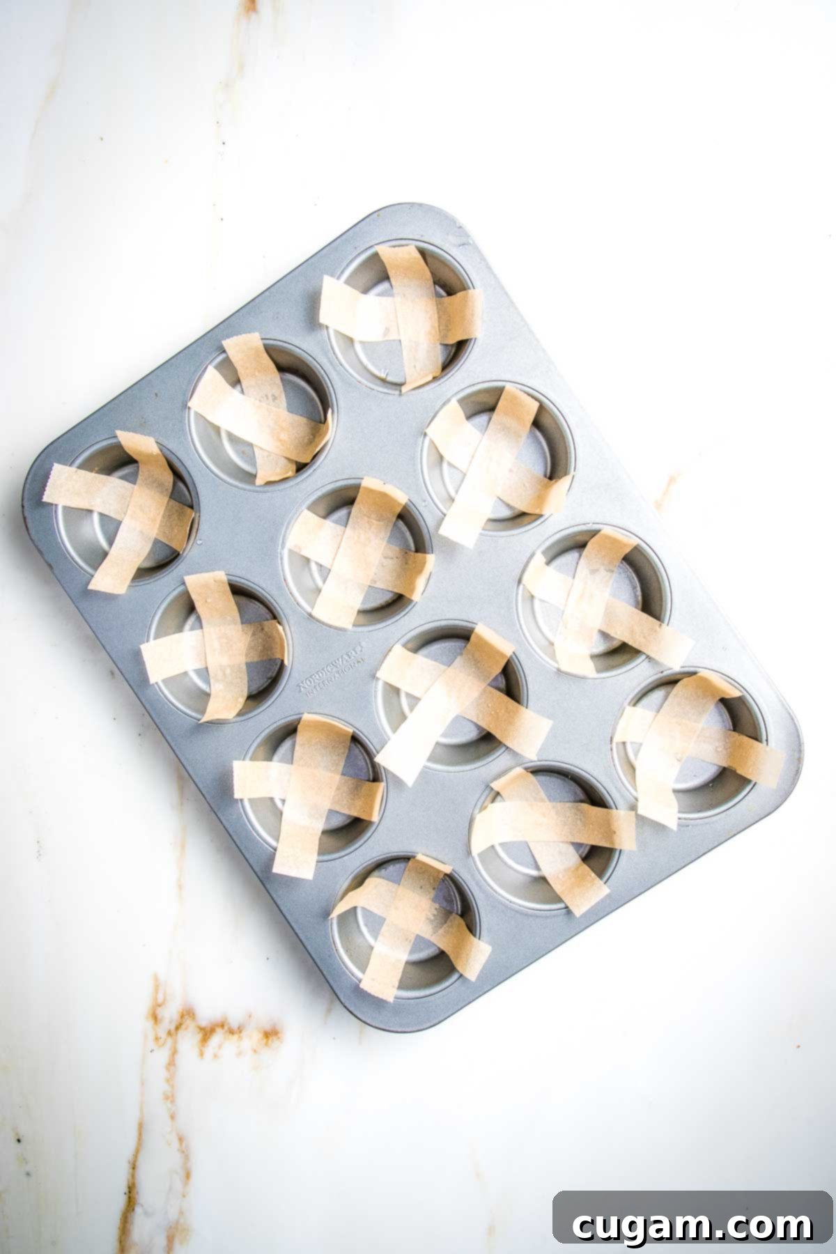 Muffin tin with strips of parchment paper before filling.