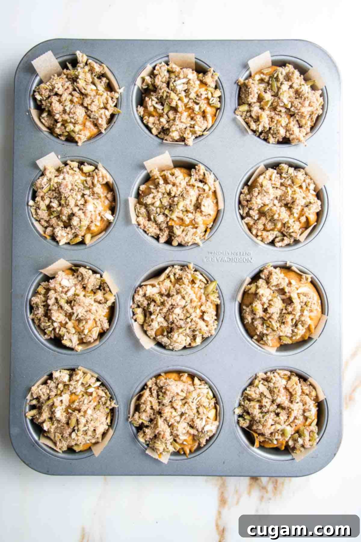 Pumpkin muffns with streusel topping muffin tins lined with parchment paper strips.