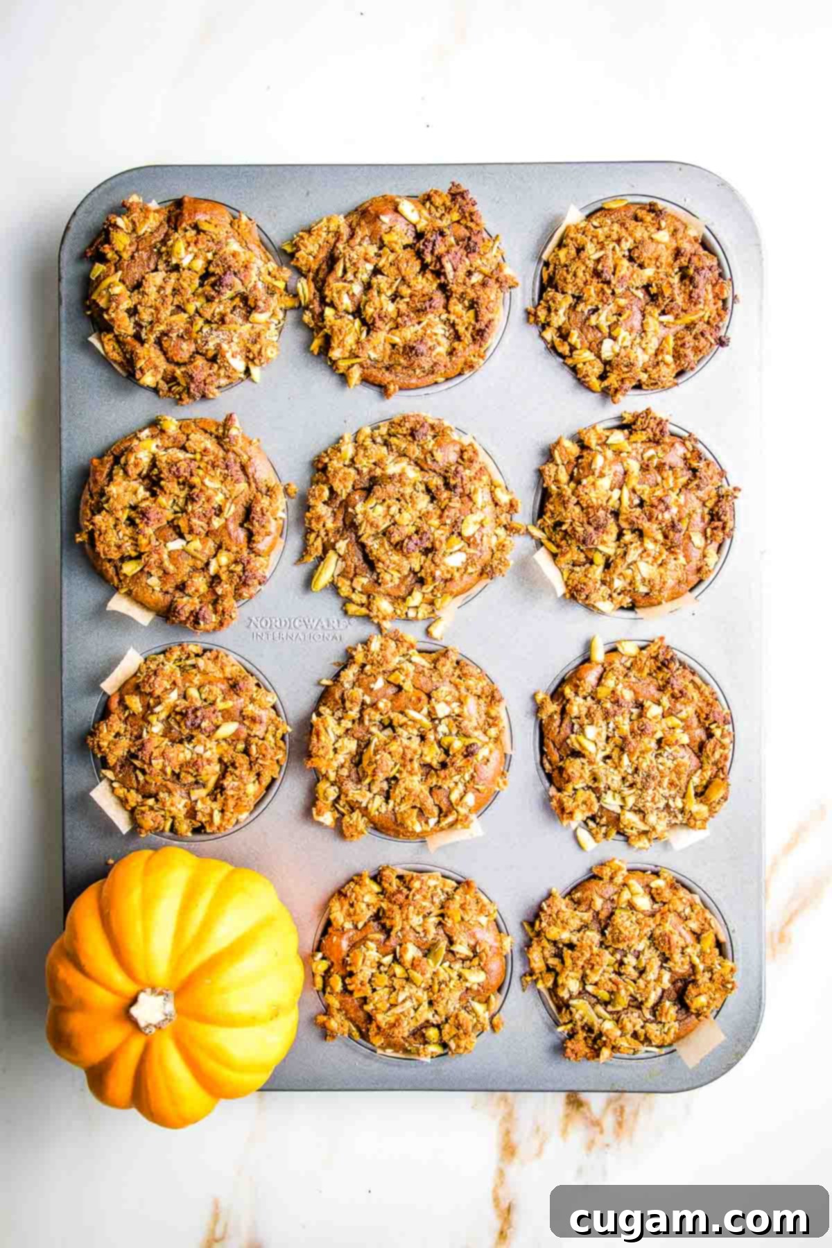 Pumpkin muffins with streusel topping baked in a tin.