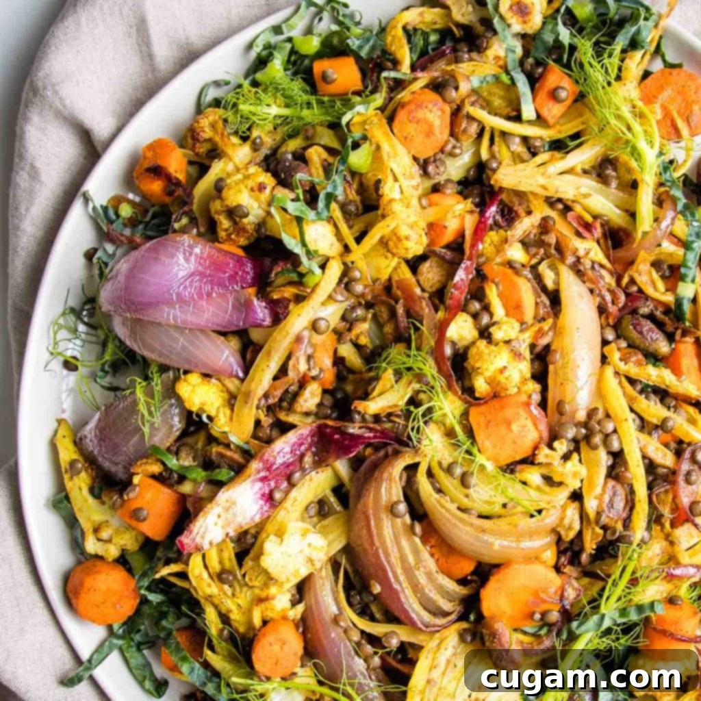 A vibrant, close-up shot of the finished lentil and roasted vegetable salad, garnished with fresh fennel fronds and additional pistachios, ready to be served.