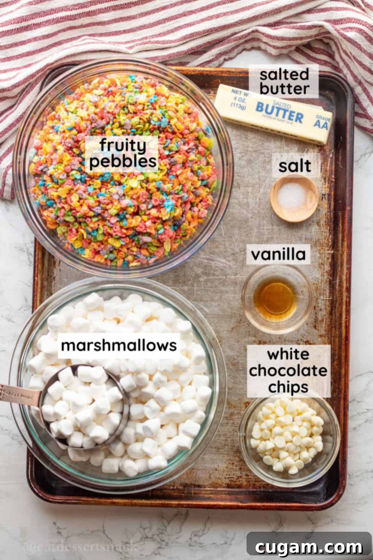 Labeled glass bowls containing Fruity Pebbles cereal, mini marshmallows, butter, and white chocolate chips.