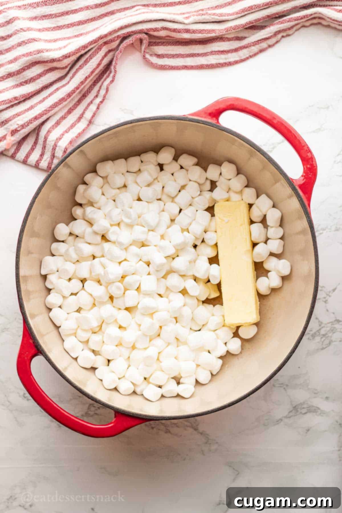 Marshmallows and butter melting together in a red pot over low heat.