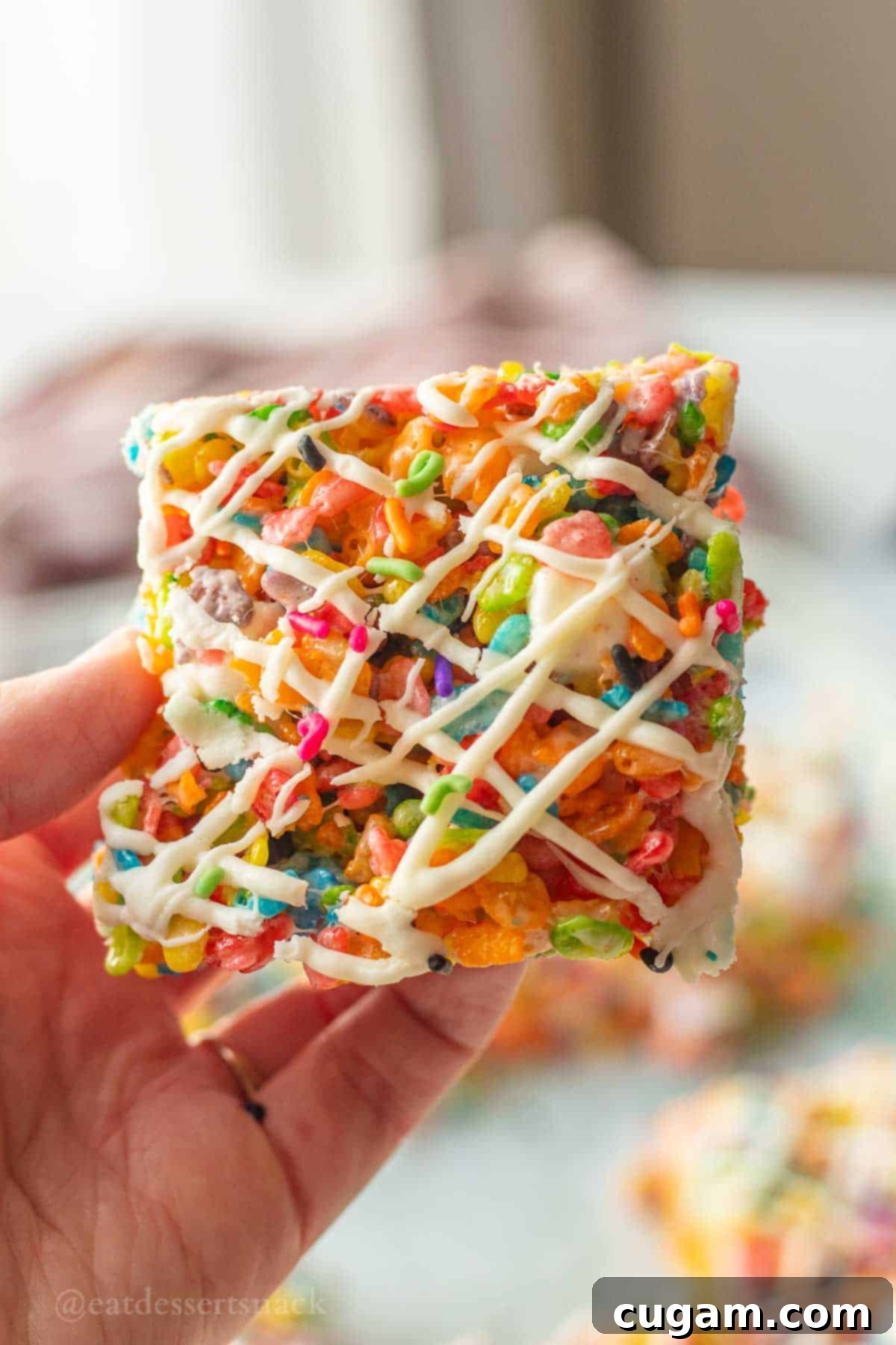 A perfect slice of fruity pebble crispy treats with a delicate white chocolate drizzle on top, highlighting its colorful layers.