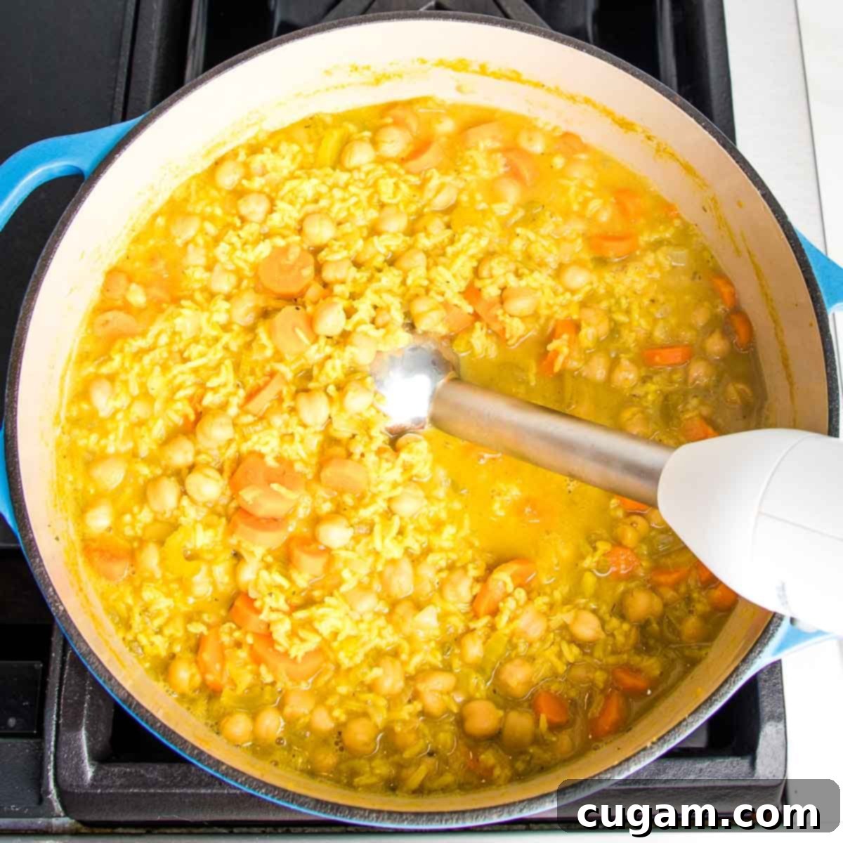 Nourishing Vegan Lemon Chickpea Rice Soup 12 Dutch oven with chickpea vegetable soup and an immersion blender partially pureeing the mixture.