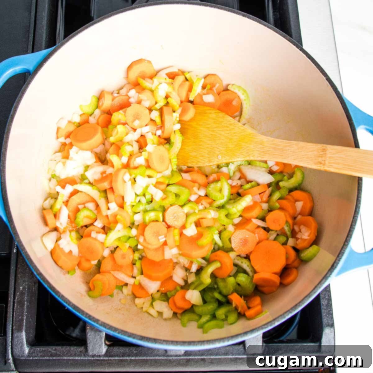 Nourishing Vegan Lemon Chickpea Rice Soup 5 Dutch oven filled with carrots, celery, onions and a wooden spoon, ready for sautéing.