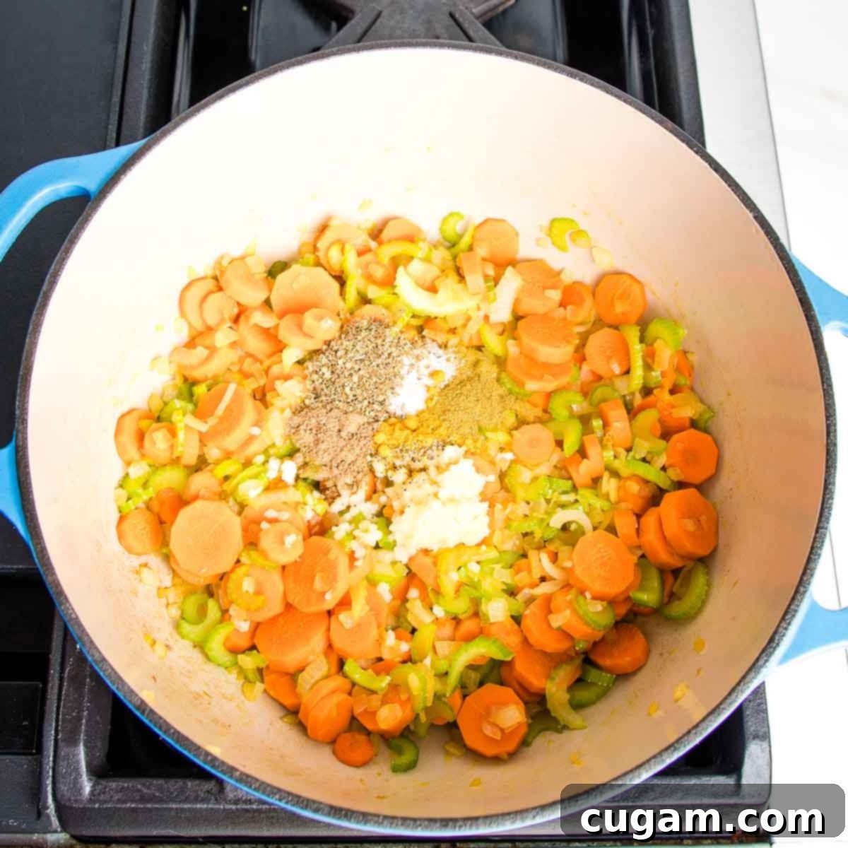 Nourishing Vegan Lemon Chickpea Rice Soup 6 Dutch oven with sautéed carrots, onion, and celery, now with aromatic spices and freshly grated garlic on top.