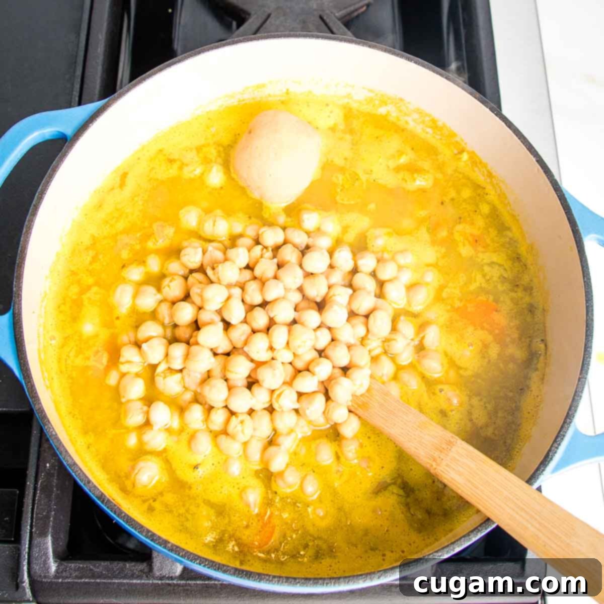 Nourishing Vegan Lemon Chickpea Rice Soup 10 Dutch oven with yellow broth, chickpeas, and a scoop of miso paste, ready to be stirred in.