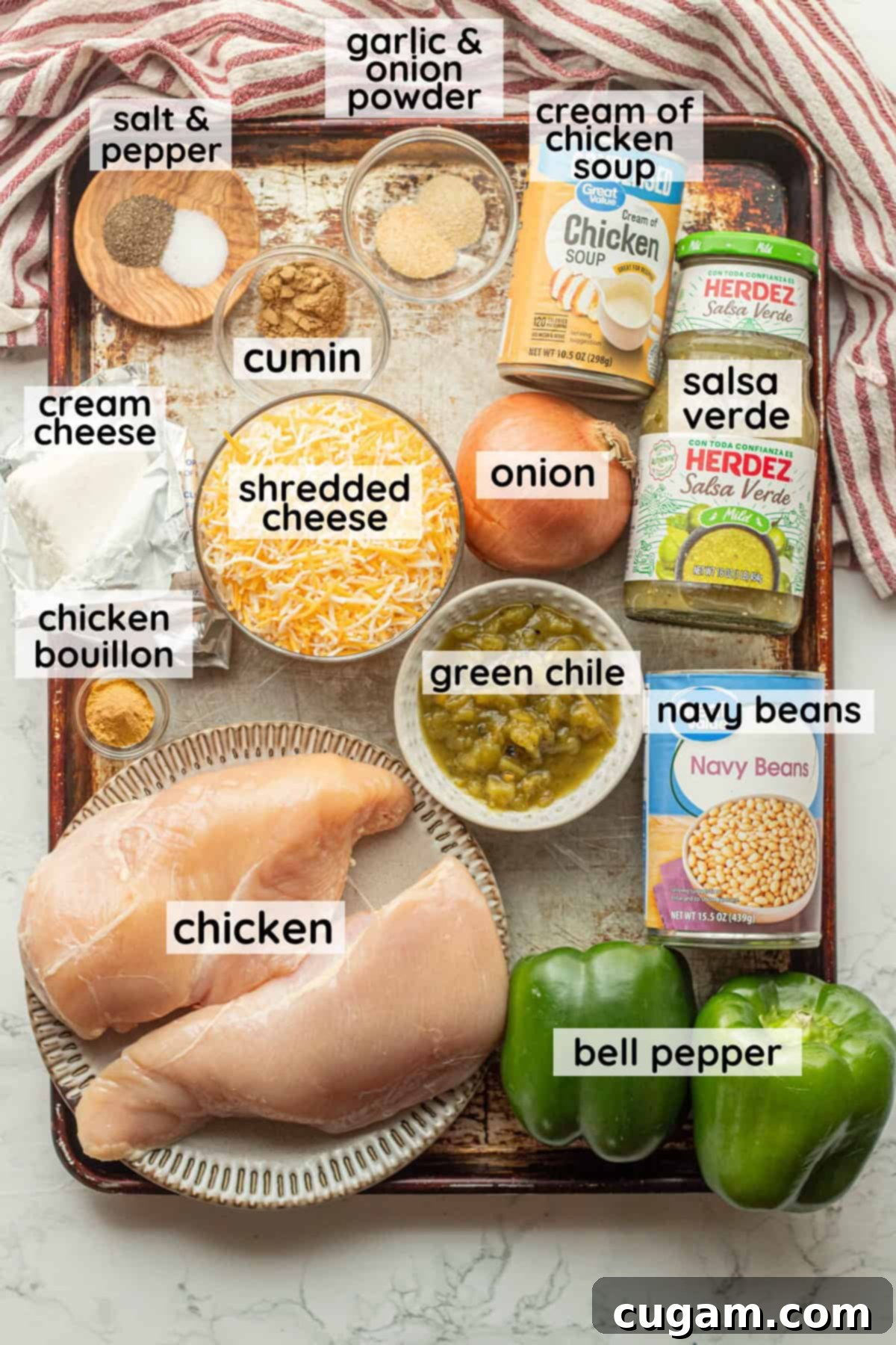 Labeled ingredients for green chile enchiladas in glass bowls on metal baking pan, ready for preparation.