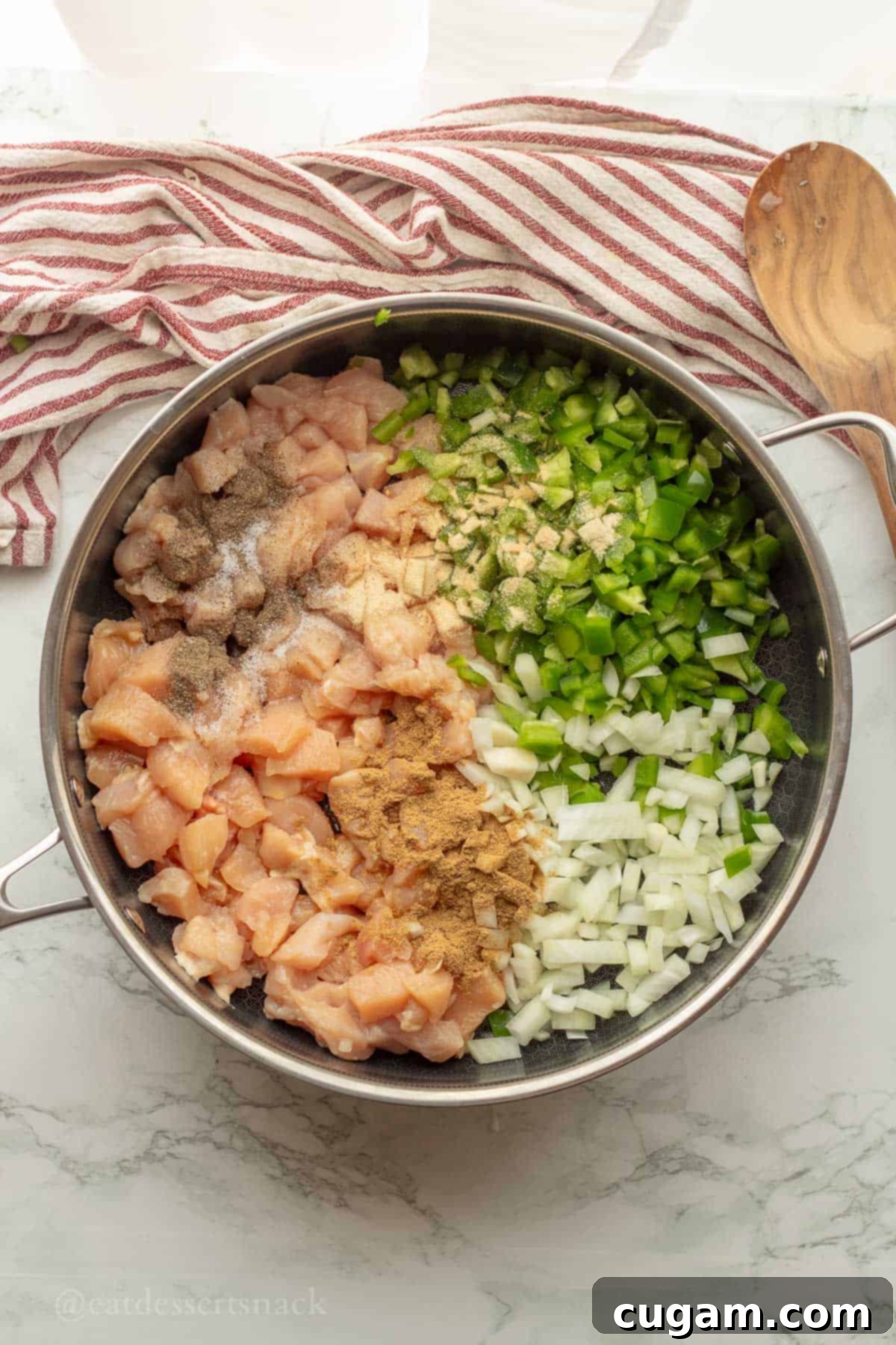 Chicken, onions, and peppers being sautéed with spices in a pan, creating a fragrant base for the enchilada filling.