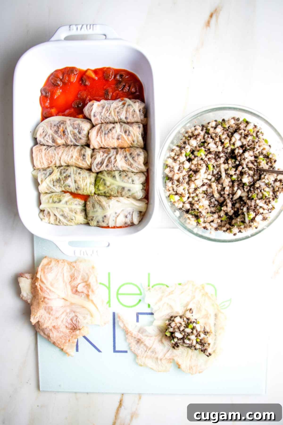 Hearty Vegan Cabbage Bundles 16 Loading cabbage rolls onto sweet and sour sauce in a baking dish.
