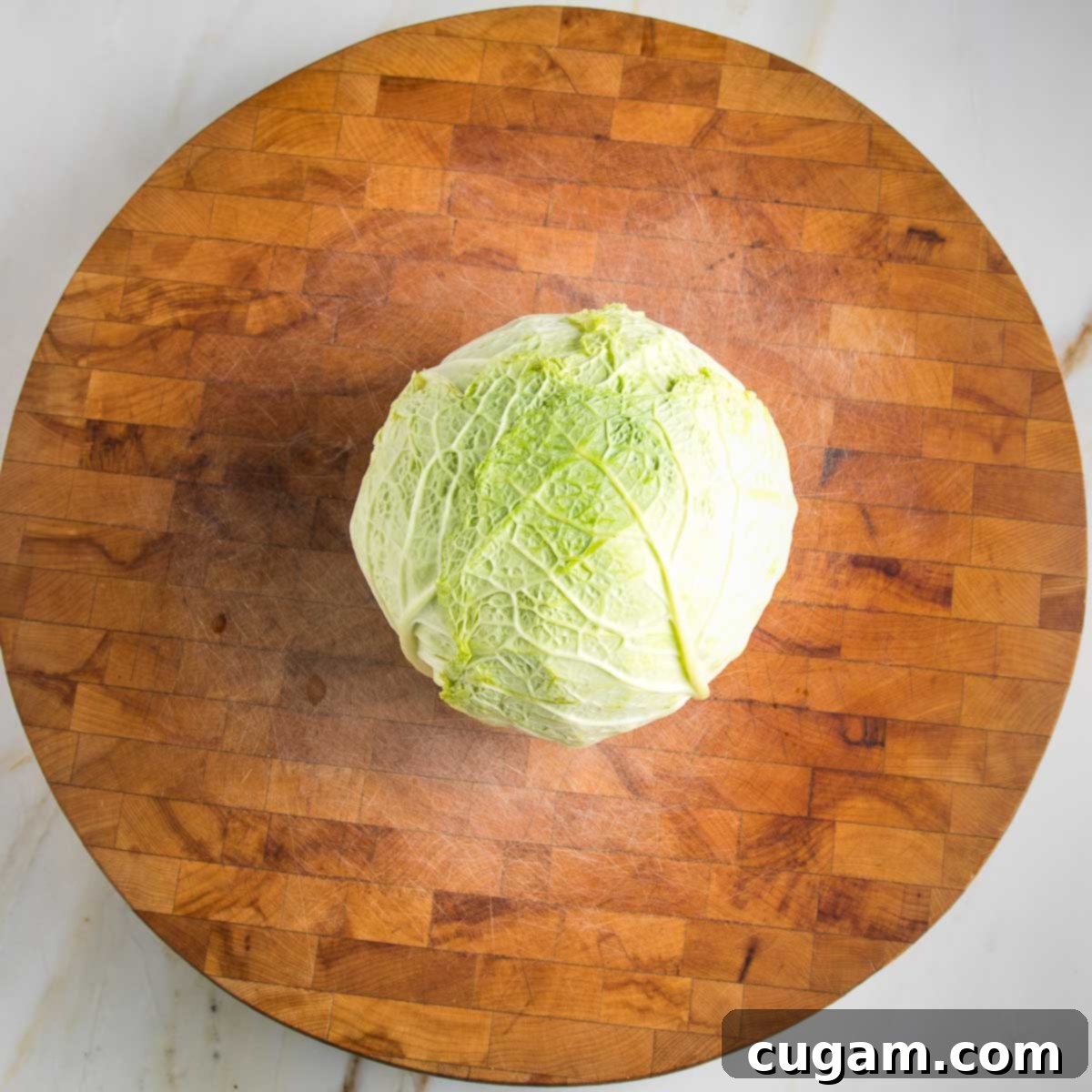 Hearty Vegan Cabbage Bundles 4 Round cutting board with a head of savory cabbage in the center.