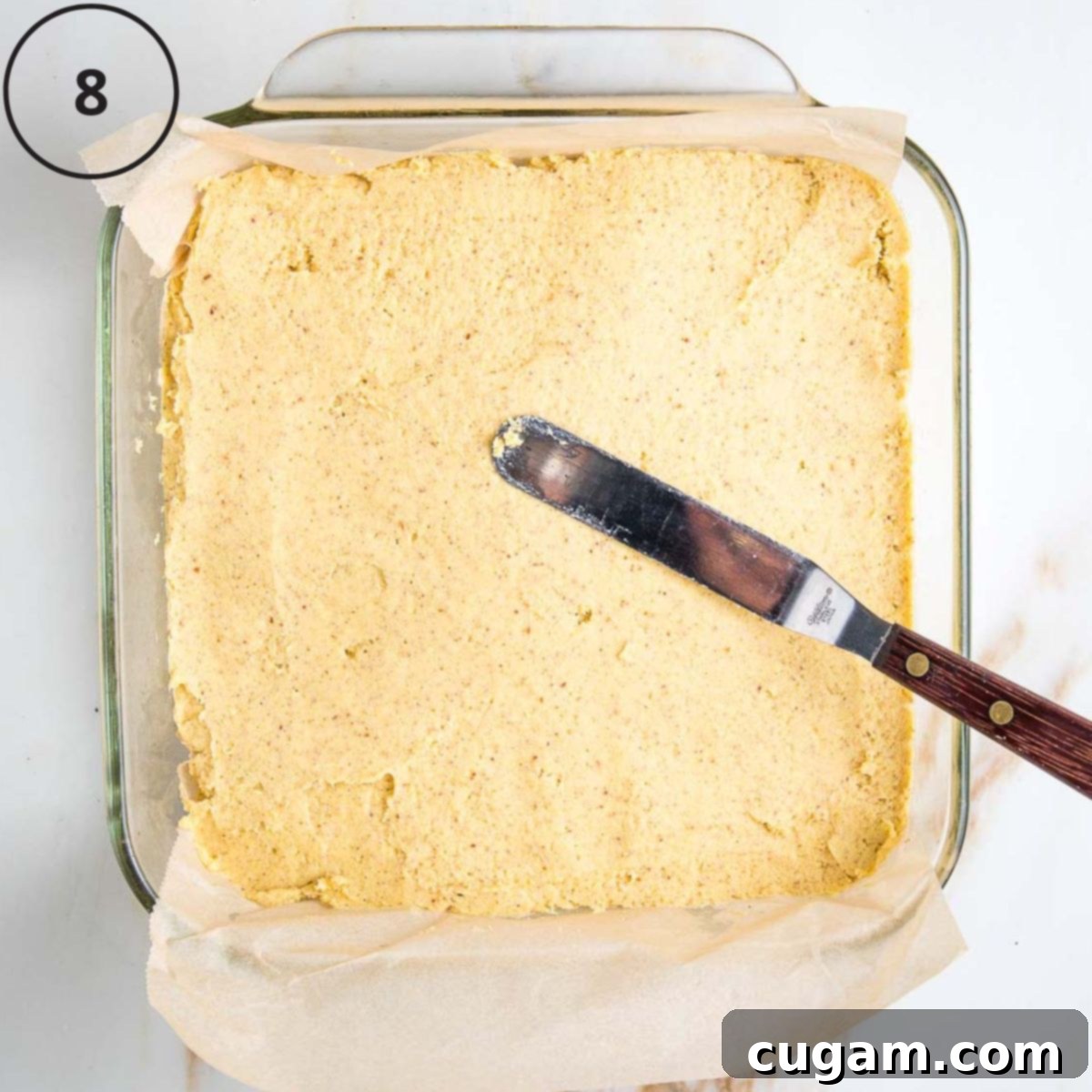 Gluten-Free Vegan Double Corn Cornbread 11 A square baking pan holds the cornbread batter, which is being carefully smoothed into an even layer using an offset spatula.