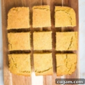 Gluten-Free Vegan Double Corn Cornbread 14 A square of golden-brown cornbread, freshly cut into nine even slices, is presented on a rustic wooden board, ready to be enjoyed.