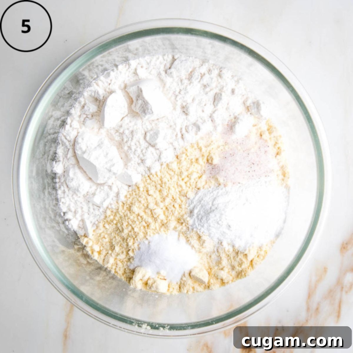 Gluten-Free Vegan Double Corn Cornbread 8 A large stainless steel mixing bowl holds an array of dry ingredients: gluten-free flour, cornmeal, salt, baking soda, and baking powder, perfectly mixed together.