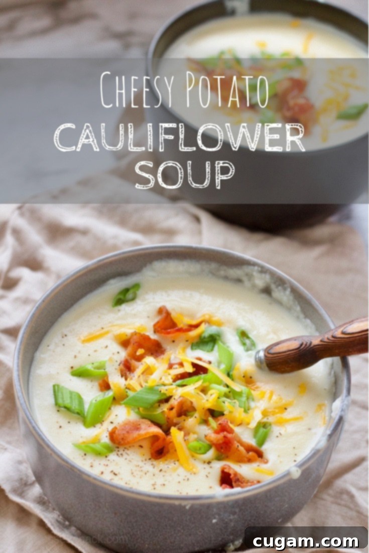 A steaming bowl of cheesy potato cauliflower soup garnished with fresh green onions, crispy bacon crumbles, and a sprinkle of cheddar cheese.