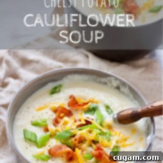 Creamy Potato Cauliflower Soup 2 A beautifully presented bowl of Cheesy Potato Cauliflower Soup, topped with fresh green onions, crispy bacon bits, and a generous sprinkle of cheddar cheese.