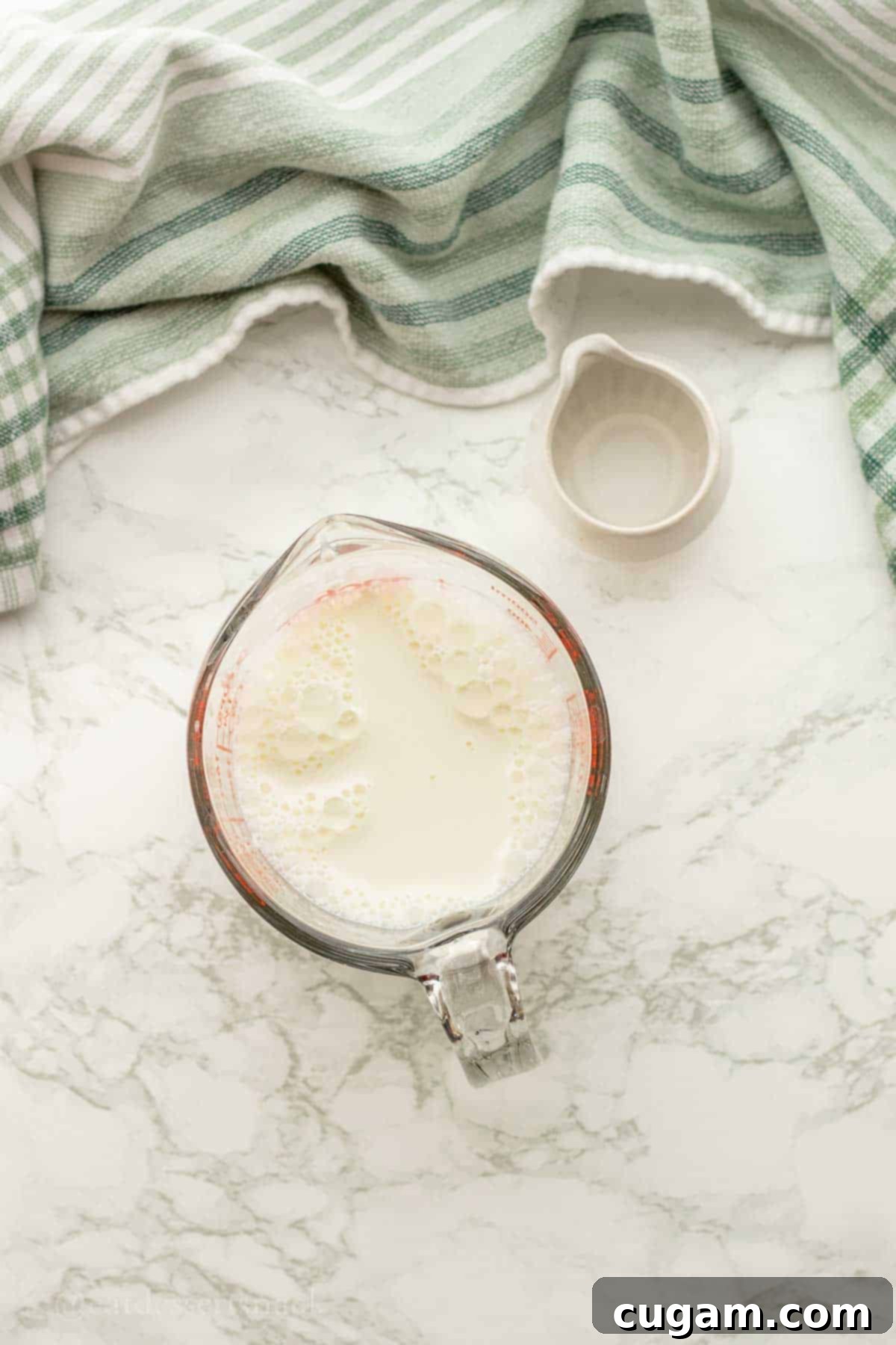 Milk and dish of vinegar on marble countertop.