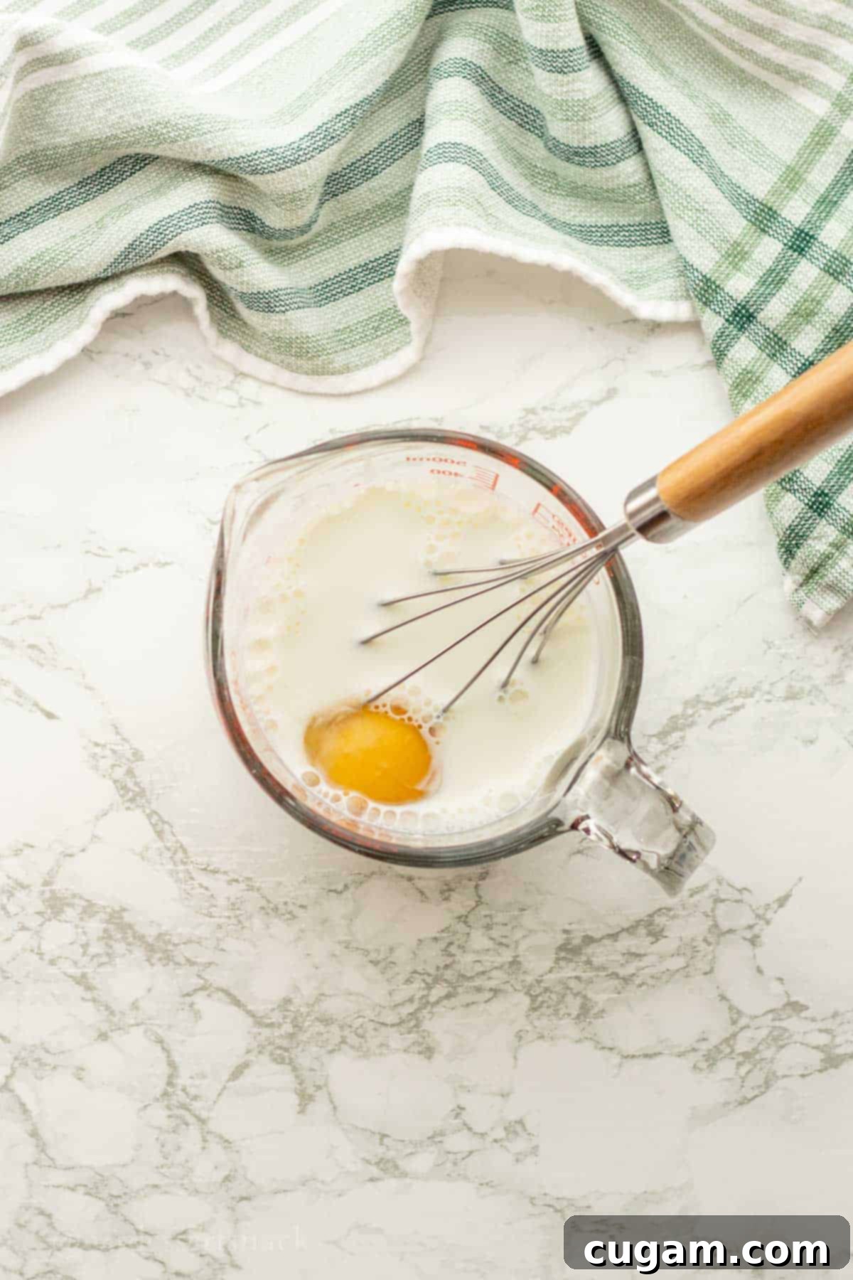 Egg in cup of milk with whisk.