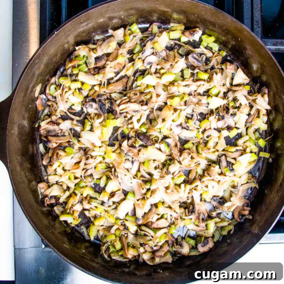Sautéed vegetables for cornbread stuffing in a cast iron skillet, with space for adding fresh herbs and greens.