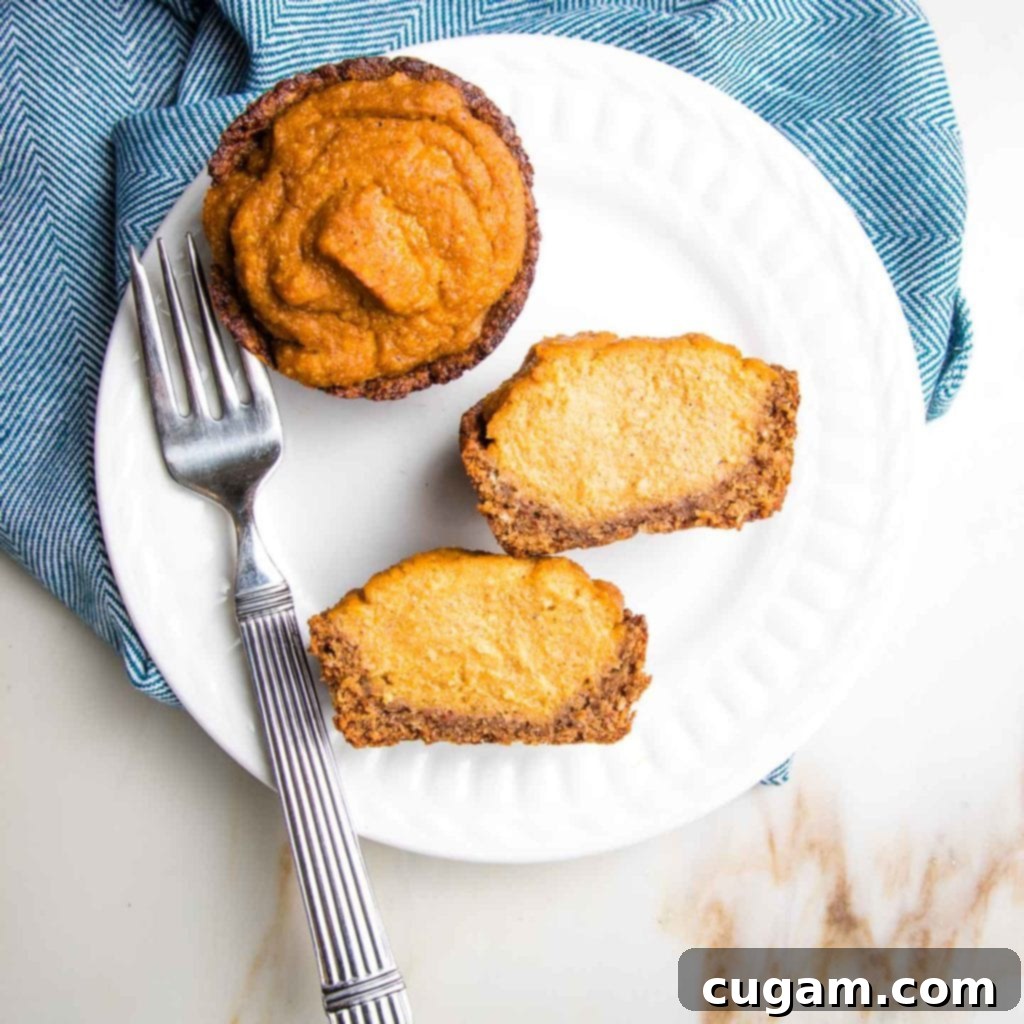 Mini pumpkin pie on a white plate, and another that's cut open to reveal a creamy interior and the gluten-free, graham cracker like crust.