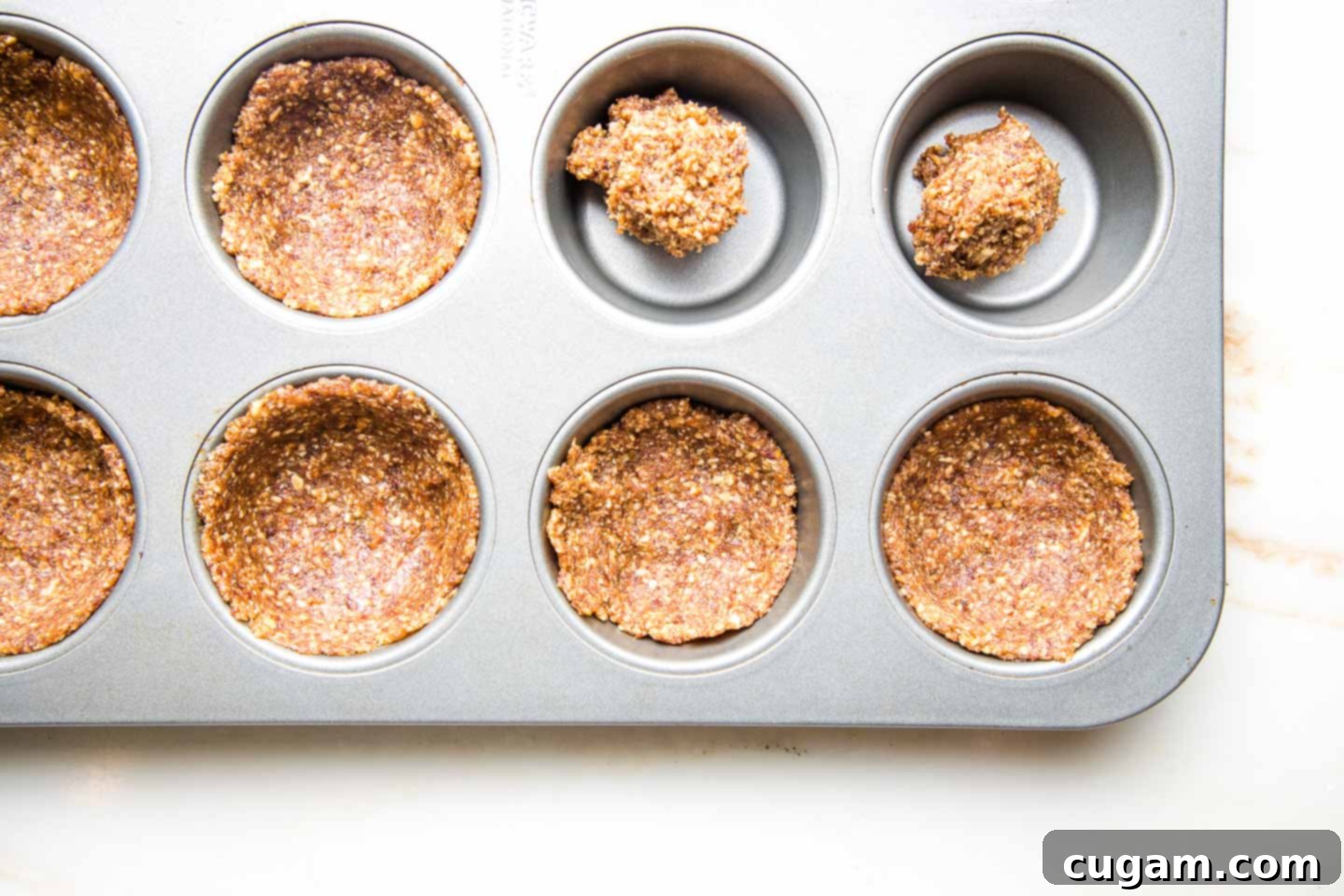 Muffin tin with pumpkin pie crust pressed up the sides. A couple tins have just the ball of dough.