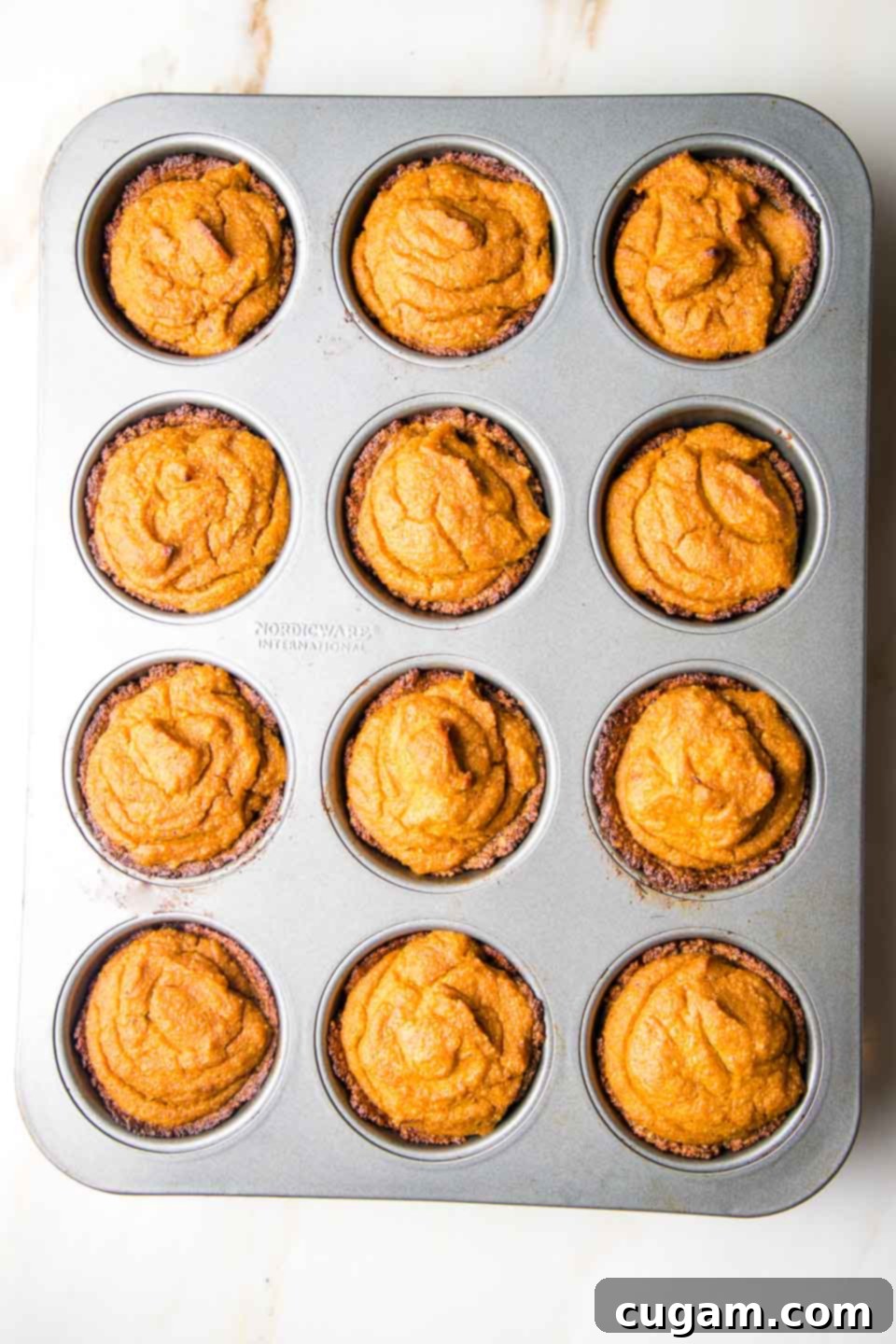Mini pumpkin pies in a muffin tin, fresh out of the oven.