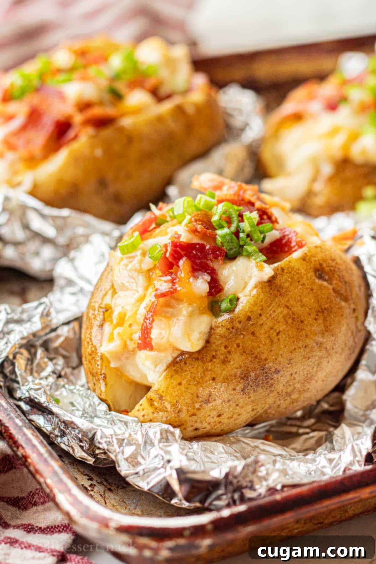 Chicken Bacon Ranch Baked Potatoes 2 Filled chicken bacon ranch potatoes on foil on baking sheet, showcasing the crispy skin and delicious topping.