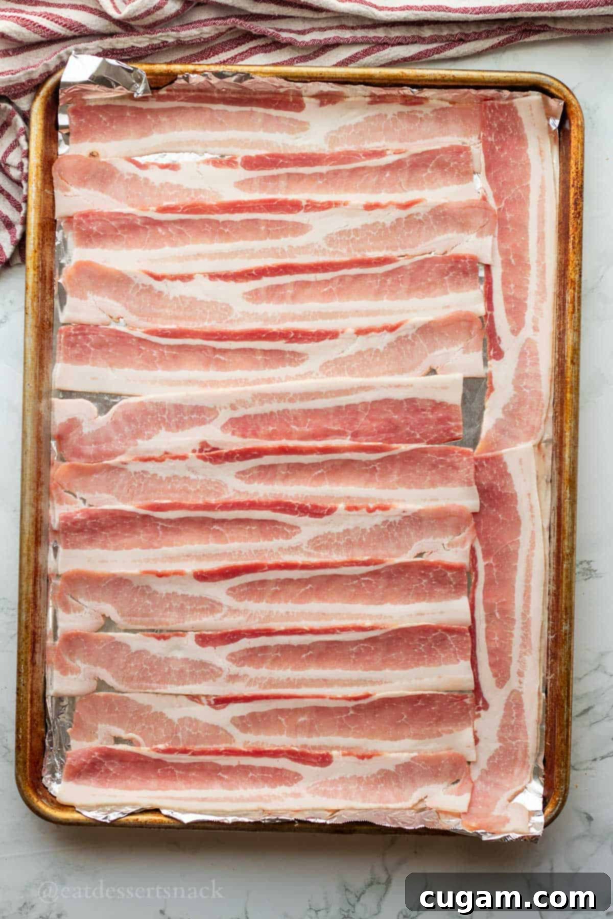 Chicken Bacon Ranch Baked Potatoes 5 Raw bacon strips neatly arranged on a foil-lined baking sheet, preparing to be cooked.