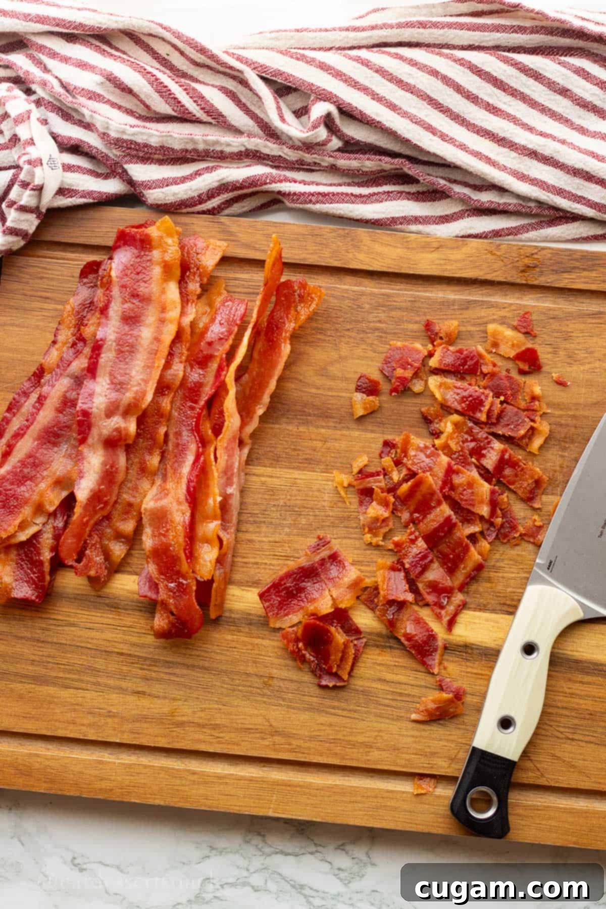 Chicken Bacon Ranch Baked Potatoes 6 Crispy cooked bacon on a wooden cutting board with a knife, ready for chopping into bite-sized pieces.