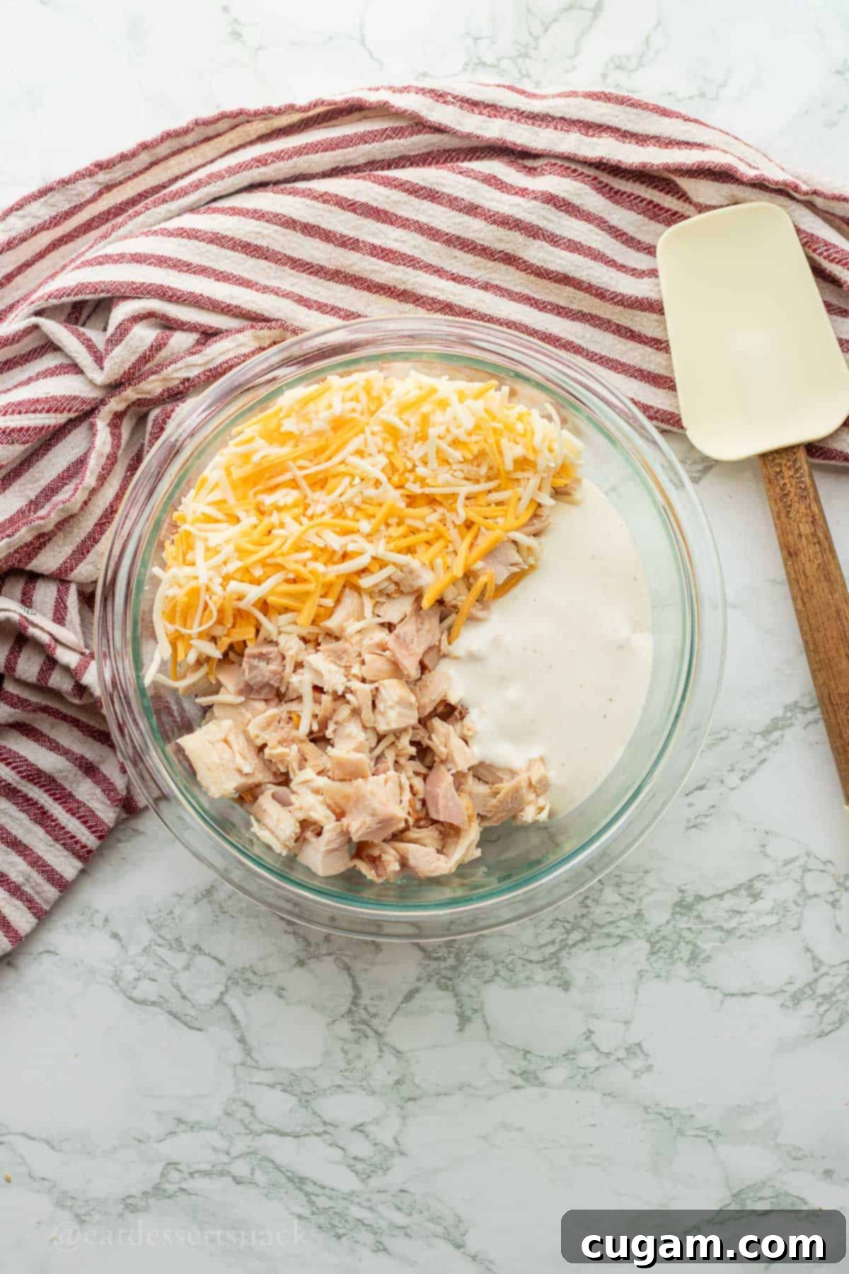 Chicken Bacon Ranch Baked Potatoes 7 Cooked chicken, shredded cheese, and ranch dressing in a mixing bowl, ready to be combined into a creamy filling.