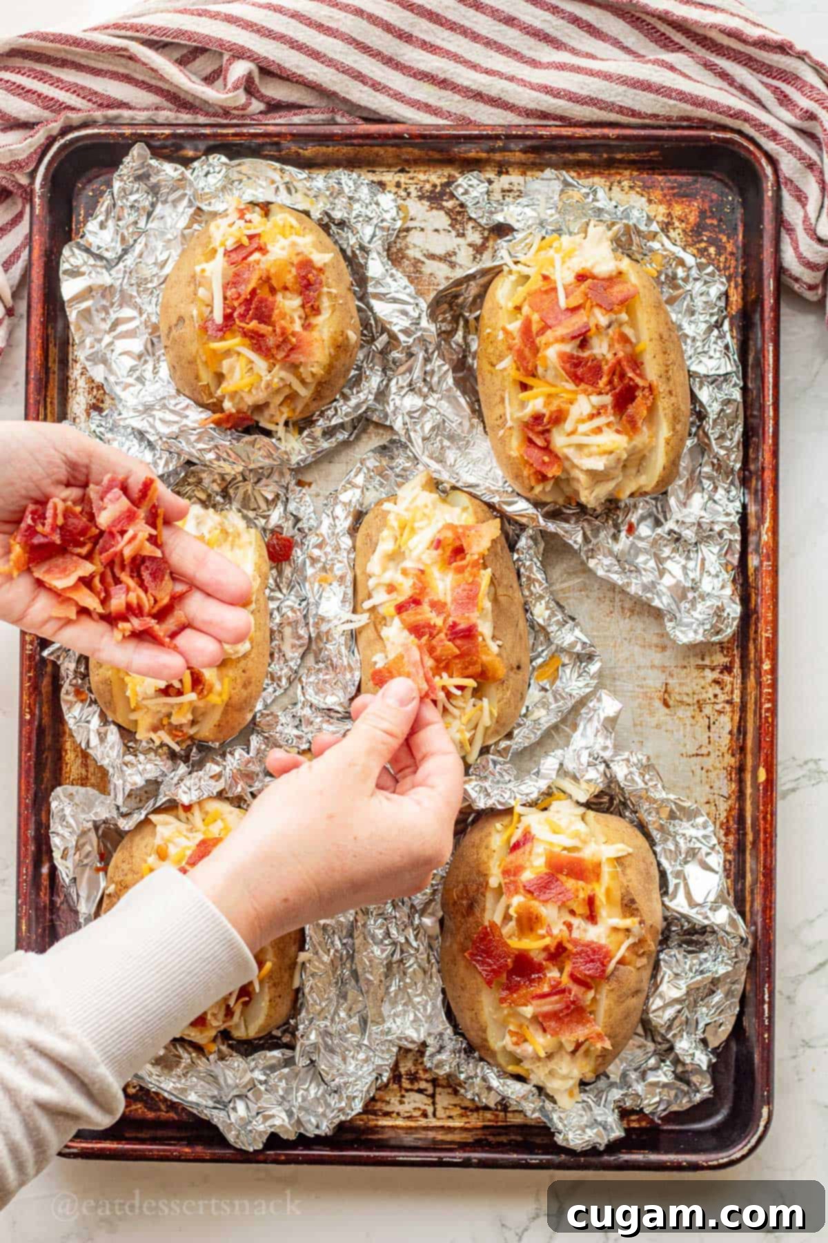 Chicken Bacon Ranch Baked Potatoes 9 Cooked bacon being sprinkled on top of baked potatoes filled with cheese and chicken, adding the finishing touch.