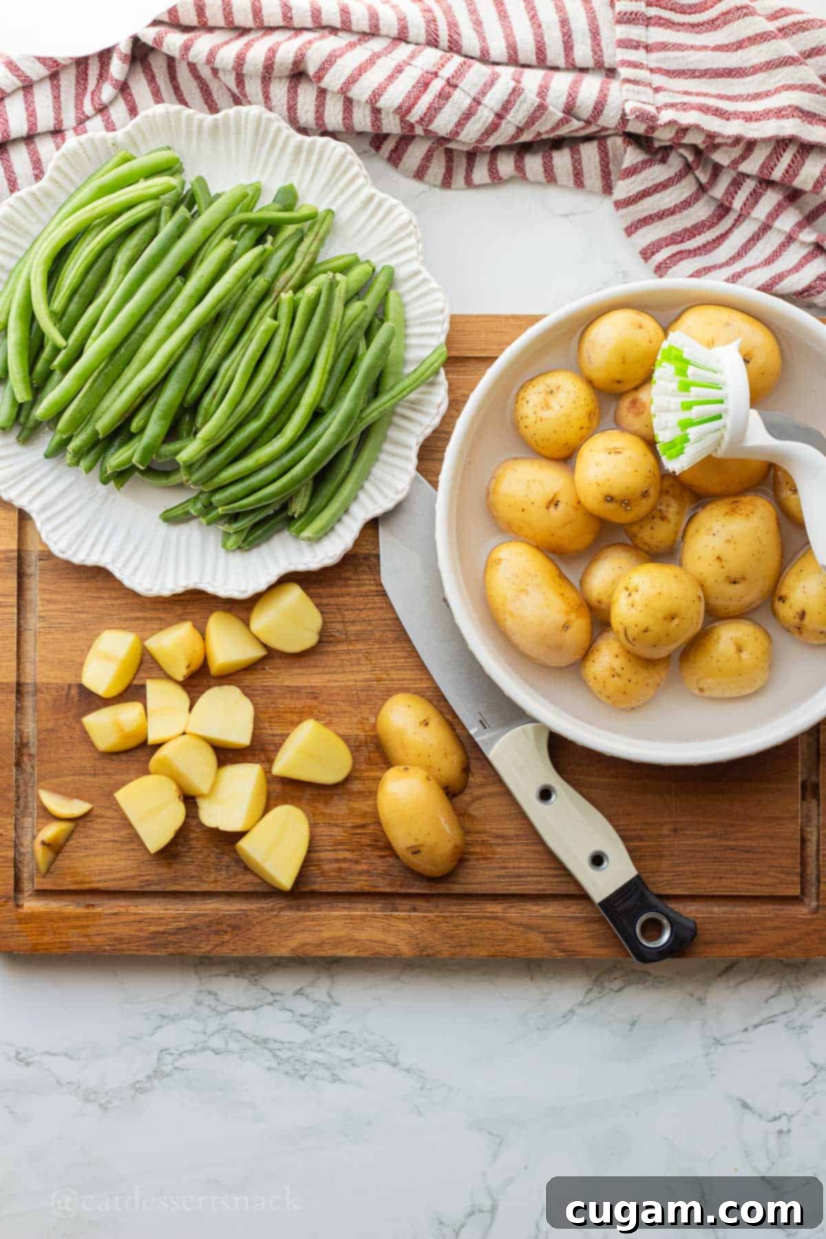 Washing potatoes and cutting them into quarters with raw green beans on wood cutting board.