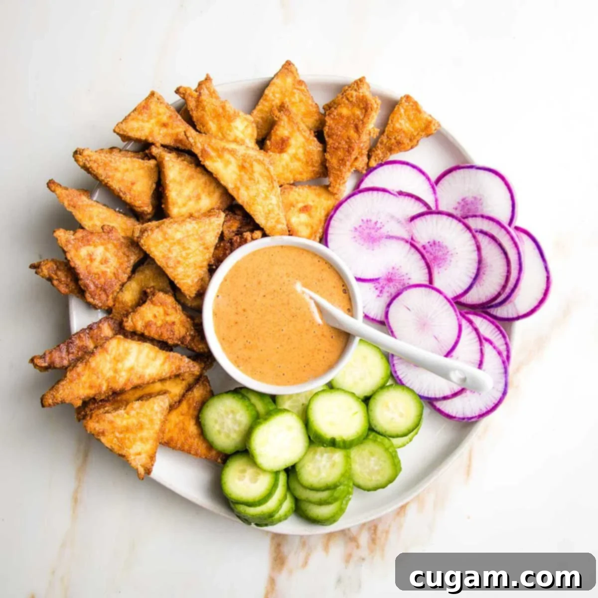 Bite-sized crispy tofu pieces arranged on a platter with a dipping sauce.