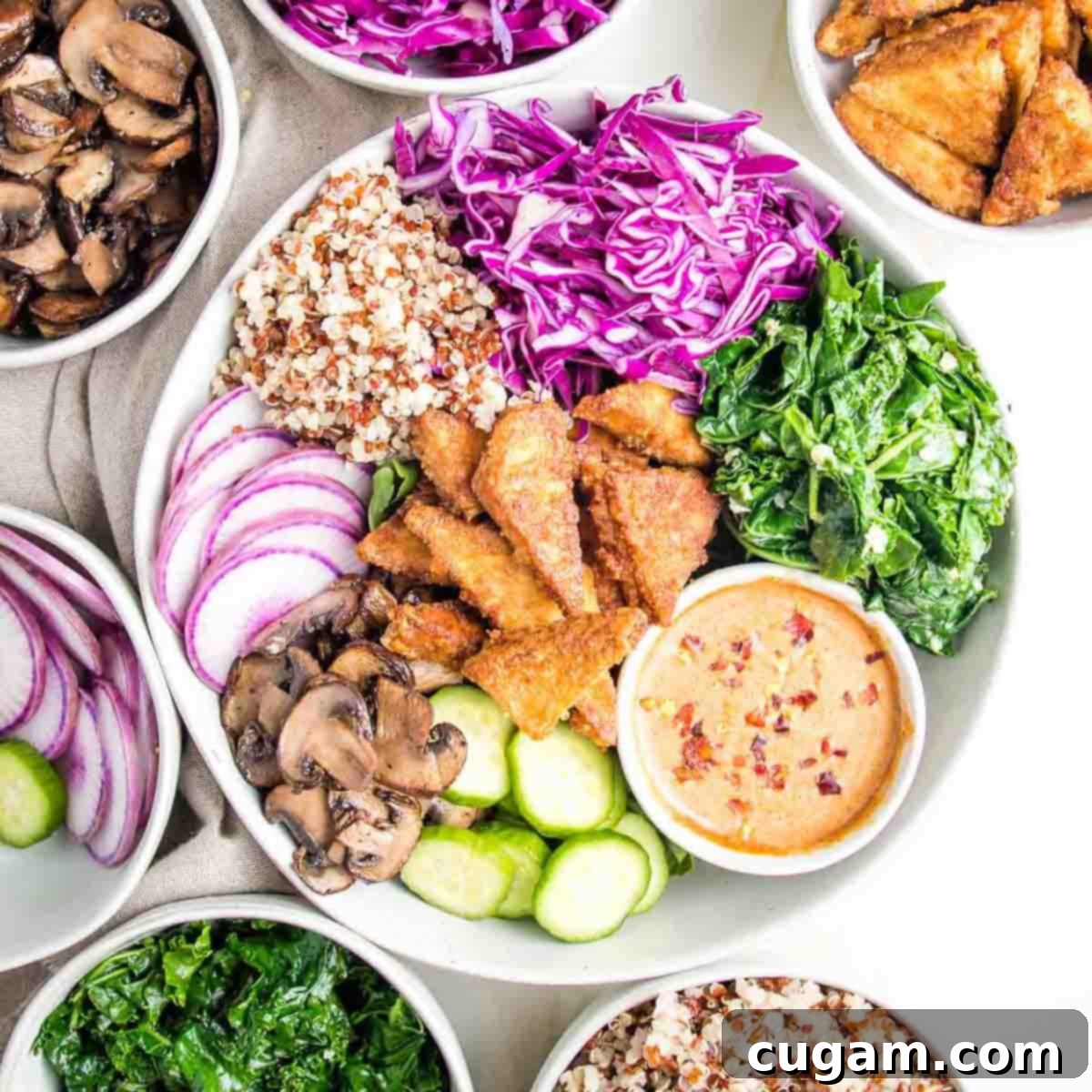 Colorful bowl of cooked and raw veggies plus crispy tofu and an almond butter sauce.