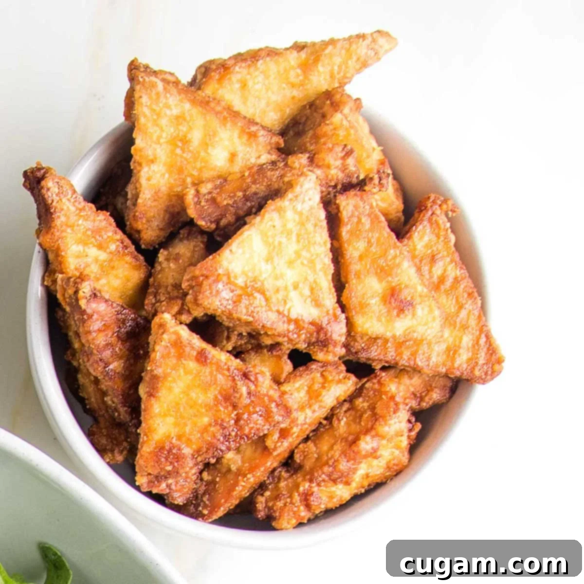Close-up of golden crispy tofu pieces on a baking sheet, illustrating perfect texture.