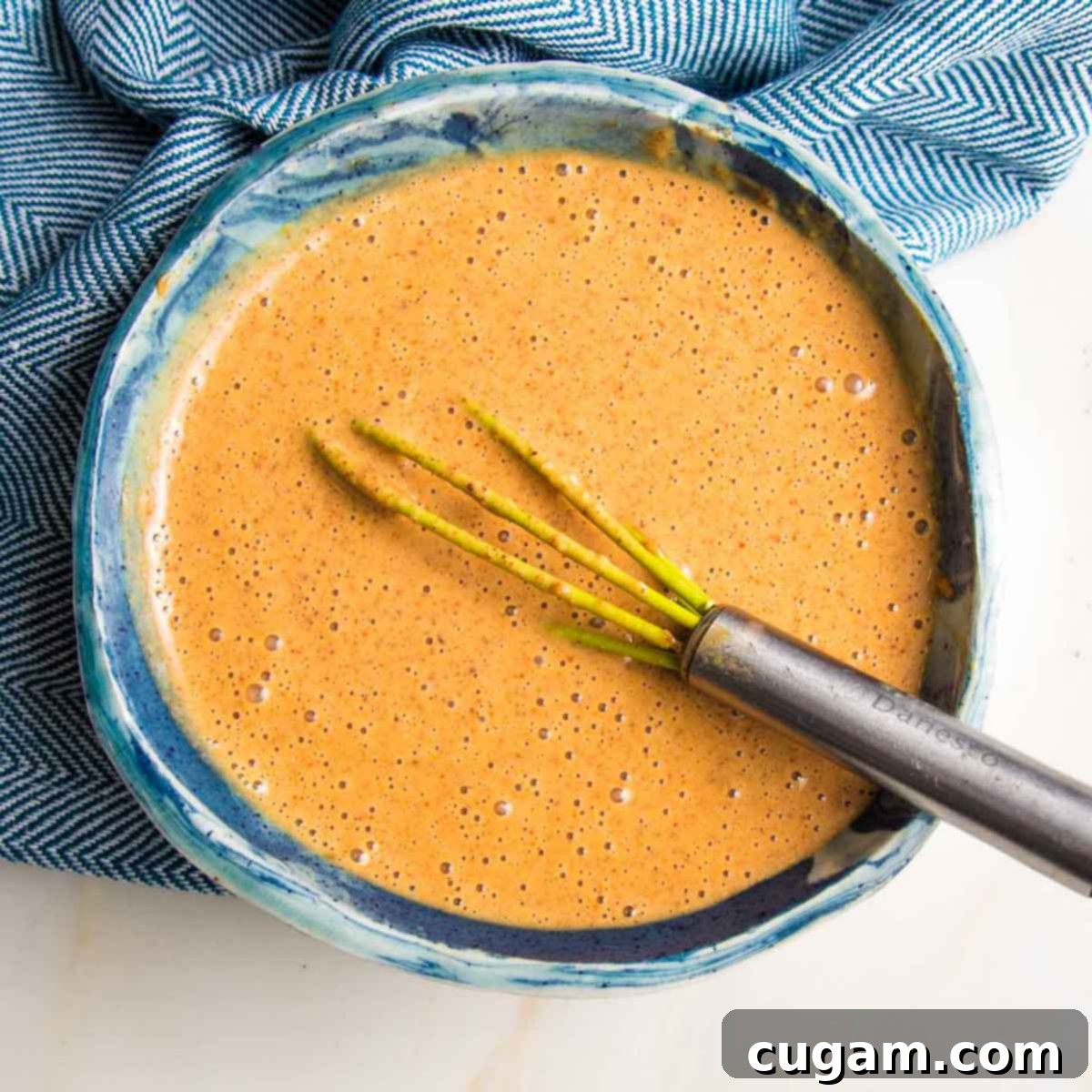 Whisking almond butter sauce ingredients until smooth and creamy.