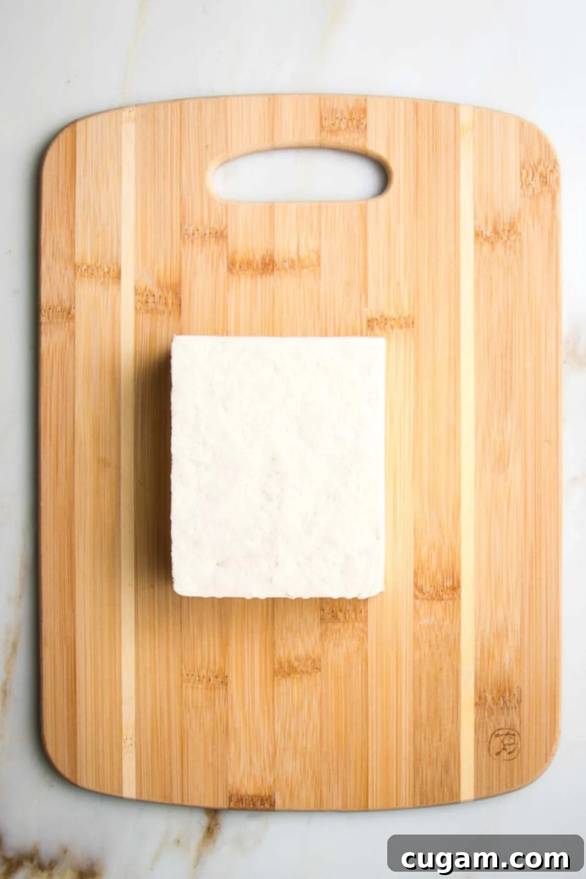 Block of tofu on a small wooden cutting board.