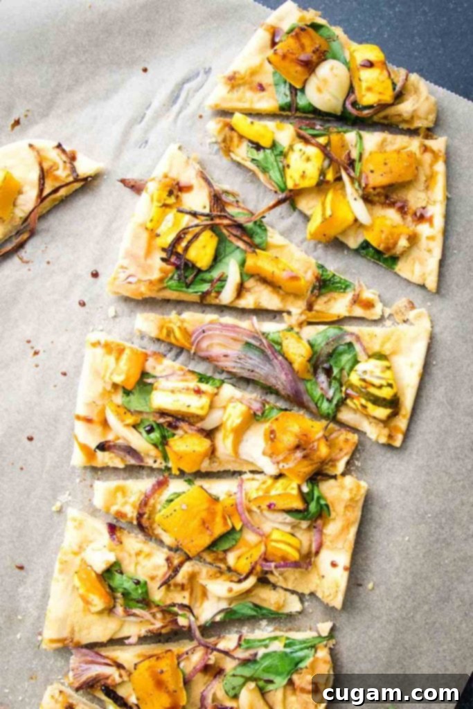 Slices of flatbread pizza lined up, topped with creamy hummus, vibrant fresh greens, and a generous amount of roasted delicata squash, sweet onions, and soft garlic, all finished with a balsamic drizzle.