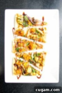 Small triangle appetizer flatbread pizza slices loaded with hummus, spinach, roasted squash, onions and garlic with a date syrup drizzle