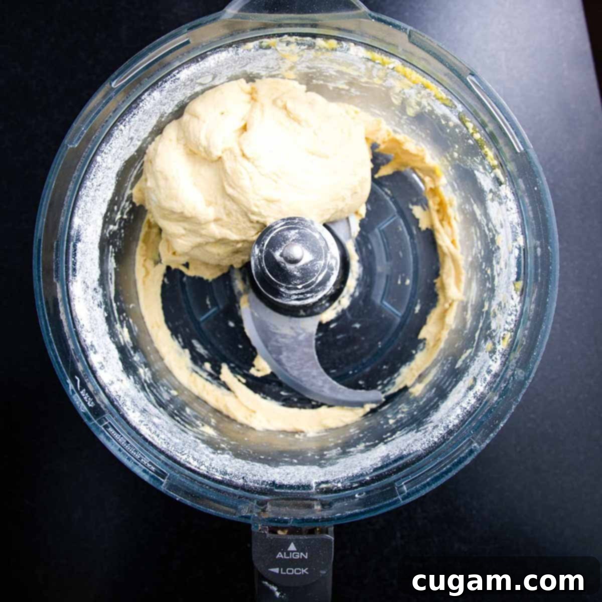 Dough forming into a ball and pulling away cleanly from the sides of the food processor bowl.