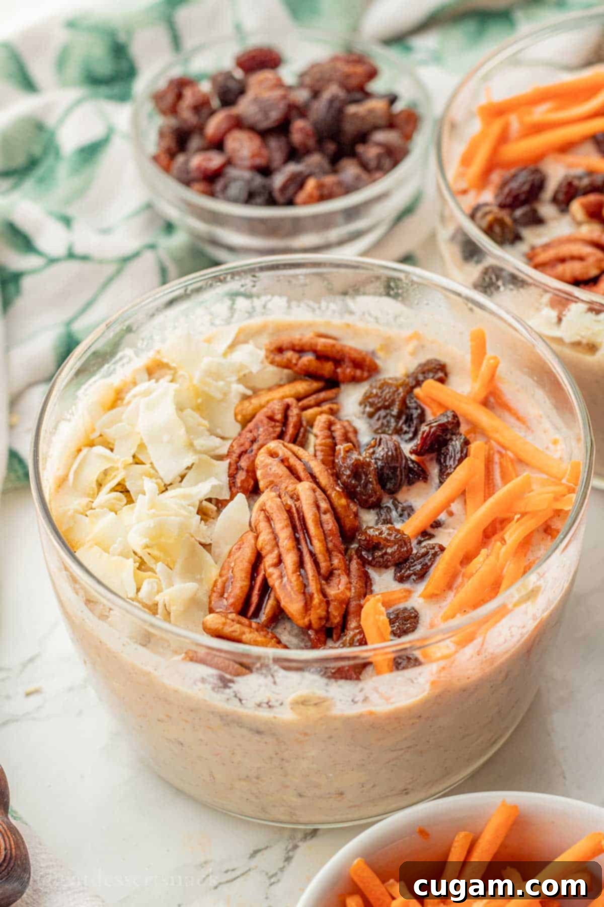 Pecans, raisins, carrots, and coconut on bowl of carrot cake overnight oats.