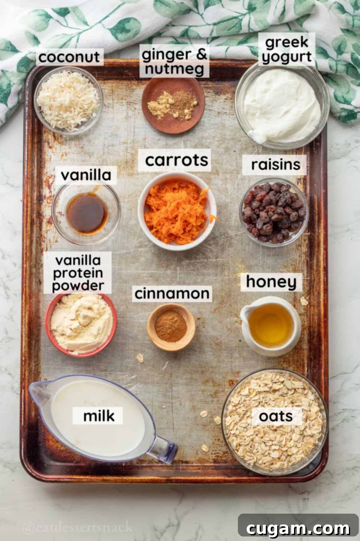 Labeled ingredients for carrot cake overnight oats in glass bowls on metal baking pan.