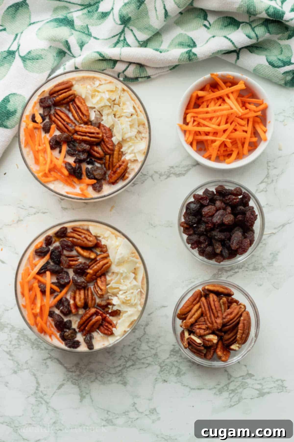 Glass bowls of carrots, raisins, and pecans around bowls of overnight oats.