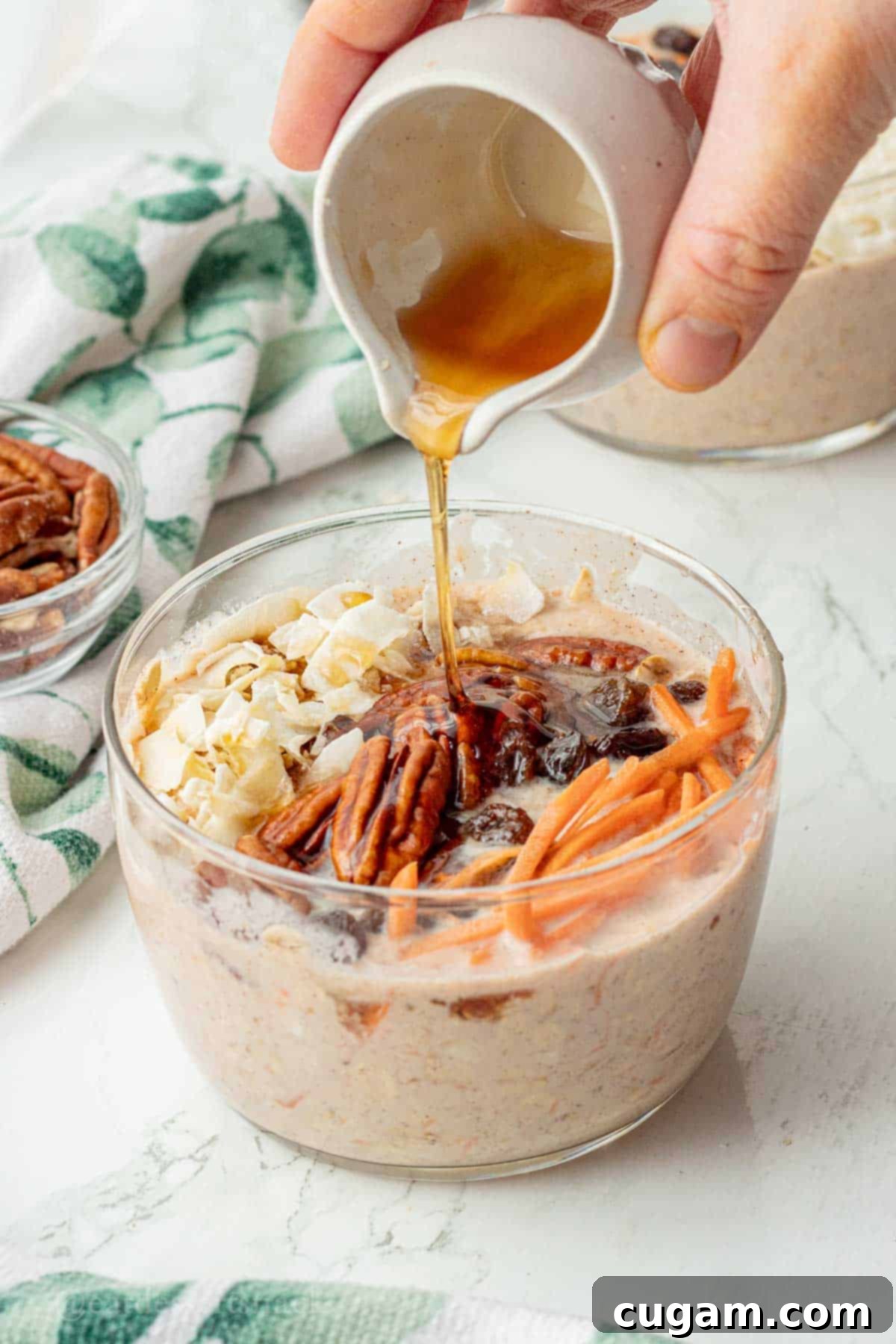 Pouring honey onto bowl of carrot cake overnight oats.
