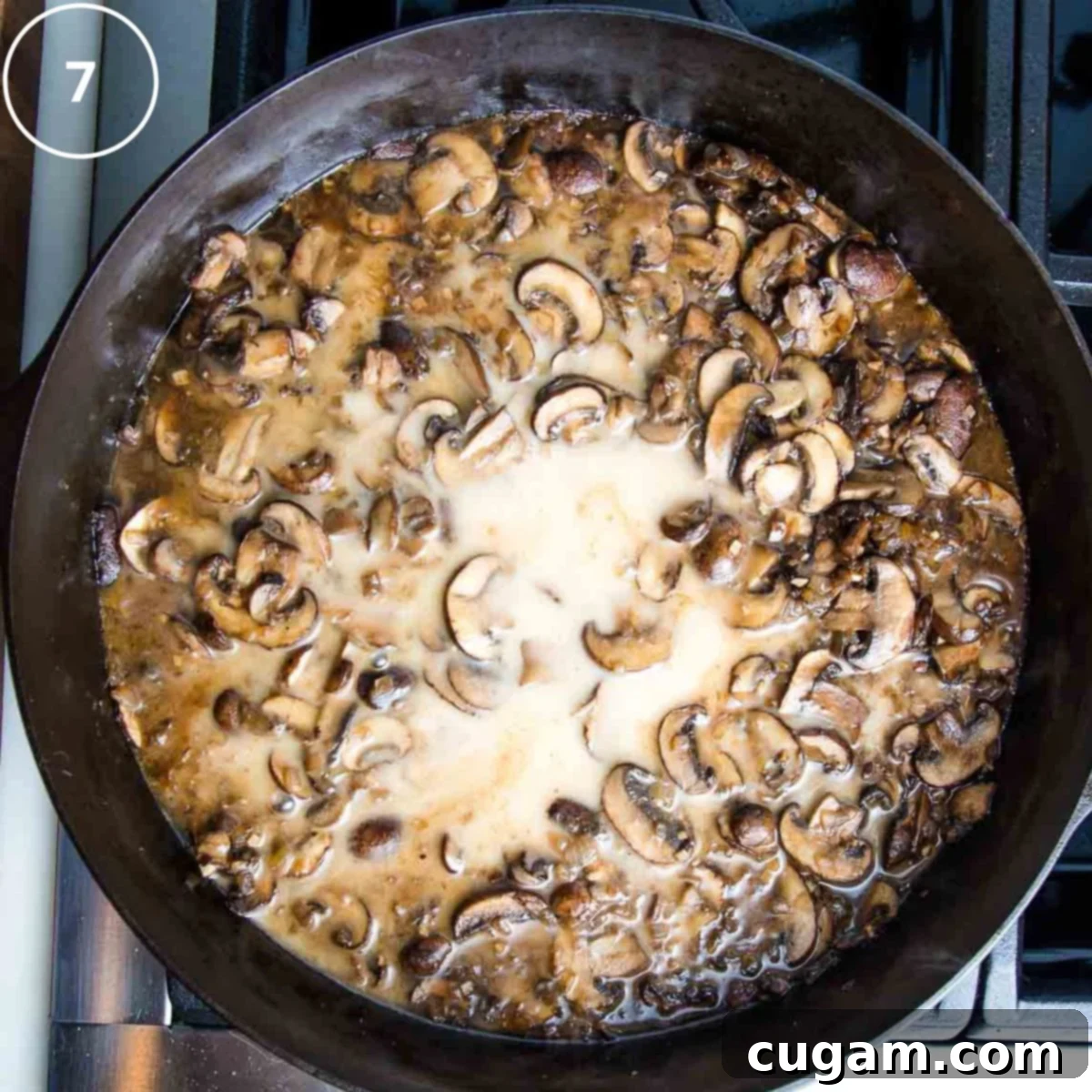Sliced mushrooms cooked in a brown sauce, with a white liquid (arrowroot slurry) being stirred into the center to thicken the sauce.